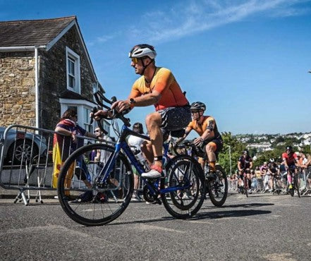 Boditronics Ambassador Craig Voisey cycling on a road section through a village